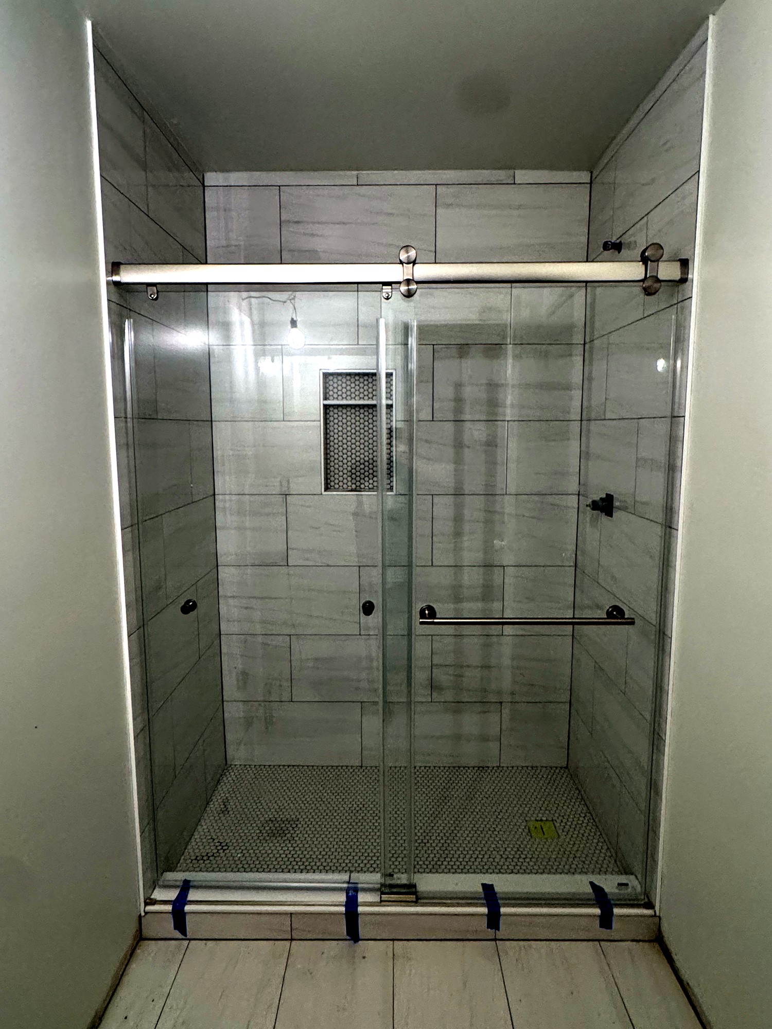Sliding frameless glass walk-in shower with tiled niche