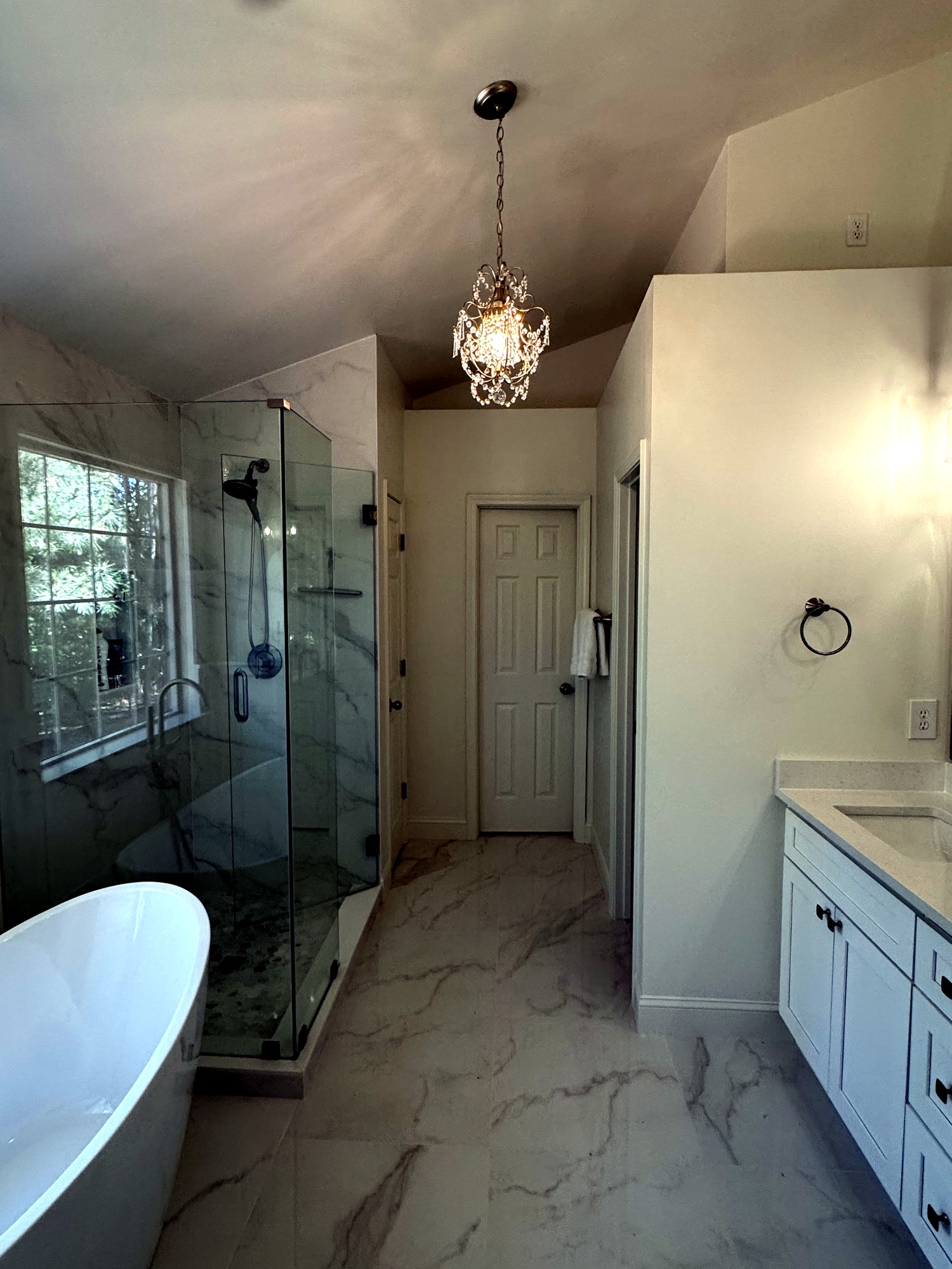 Walk-in glass shower next to freestanding soaking tub in Forsyth County bathroom remodel