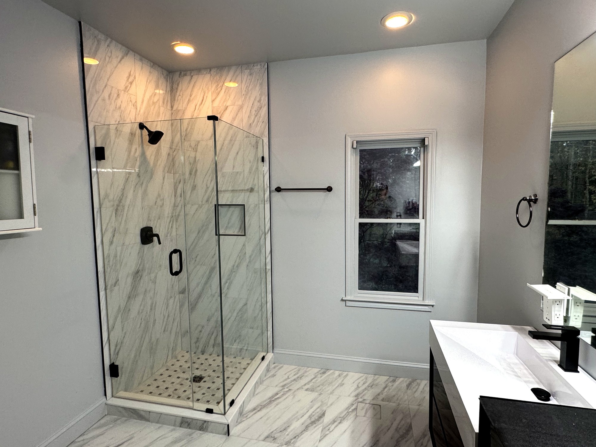 Frameless glass corner walk-in shower with marble-look tile and black fixtures, Cumming GA