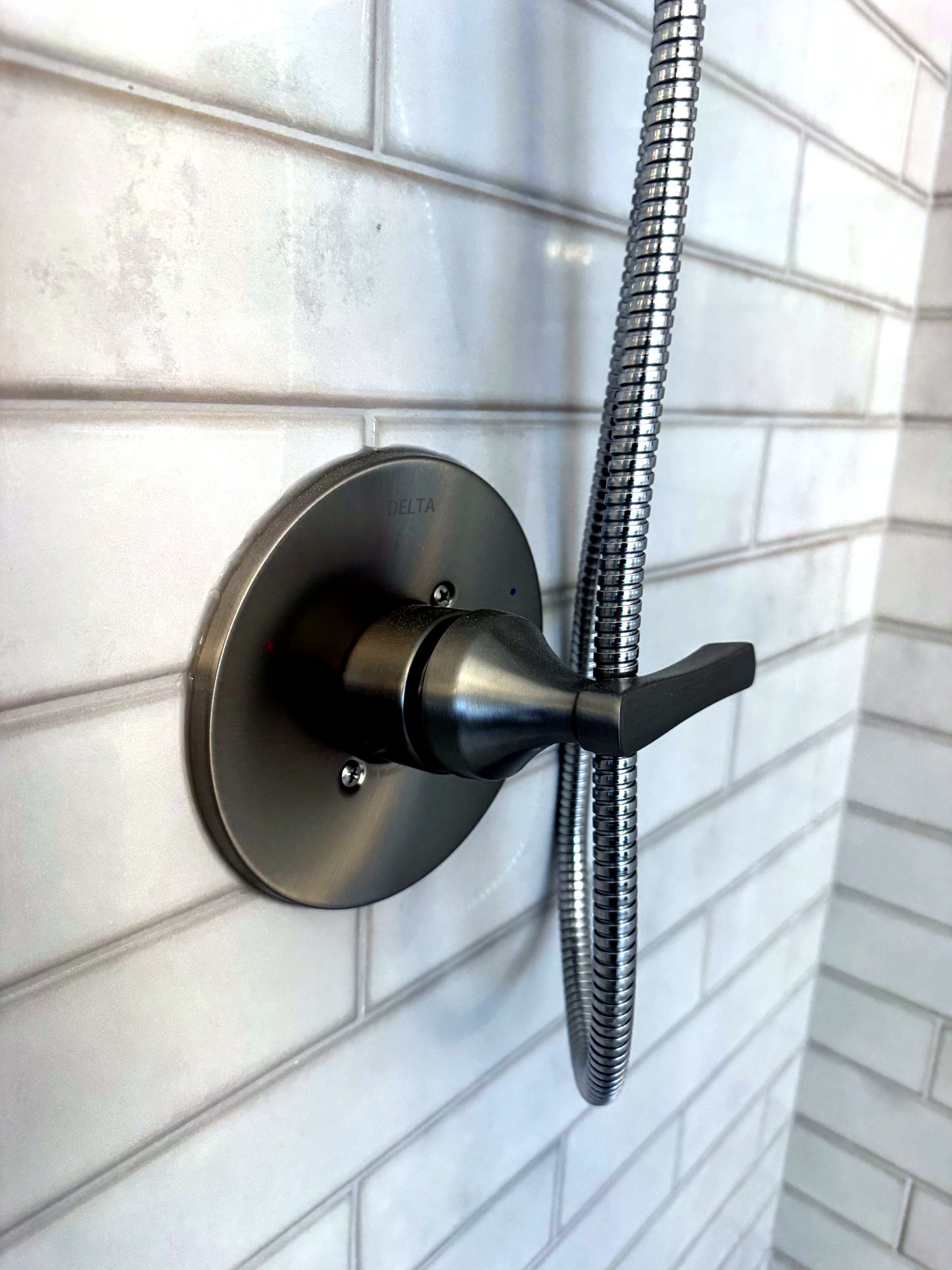 Close-up of Delta shower valve on subway tile wall
